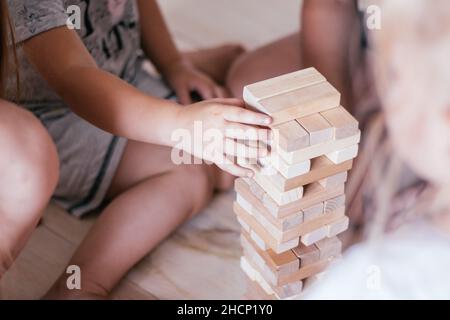 Verschwommene Kinderhände spielen Spiel mit Turm aus Holzblöcken Stockfoto