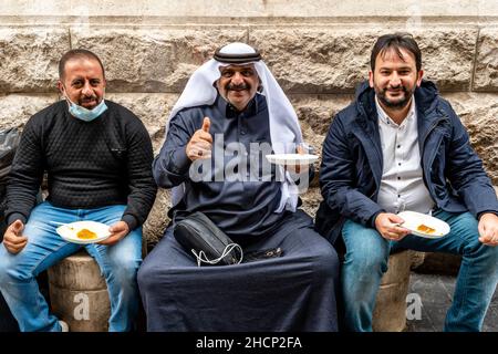 Einheimische Männer, die vor Habibah’s Konditorei/Süßwarenladen sitzen, essen Kunafa, Downtown, Amman, Jordanien. Stockfoto