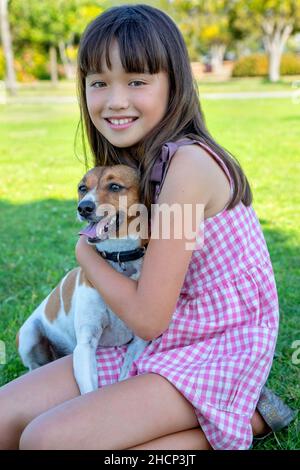 Ein neunjähriges Mädchen mit ihrem Hund im Park Stockfoto