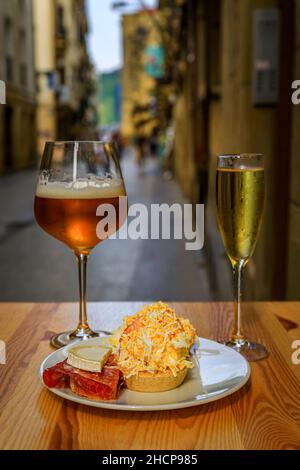 Traditionelle Pintxos mit russischem Salat und Serrano iberico Schinken Tostada mit Bier und Cava im Freien in einer Bar in San Sebastian, Baskenland, Spanien Stockfoto