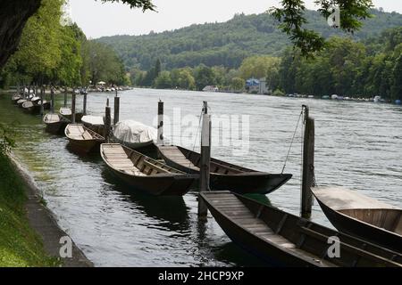 Holzboote namens Weidling in deutscher Sprache liegen in einer Reihe am Rheinufer in Schaffhausen, Schweiz. Stockfoto