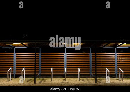 Ein leerer Fahrradstand wurde während einer Pandemie im Stadtpark vergossen. Treffpunkte ohne Menschen. Das Foto wurde in der Nacht mit künstlicher Straßenbeleuchtung aufgenommen Stockfoto