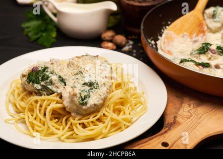 Portion leckere Fleischbällchen mit Spinat in einer cremigen Sauce Stockfoto