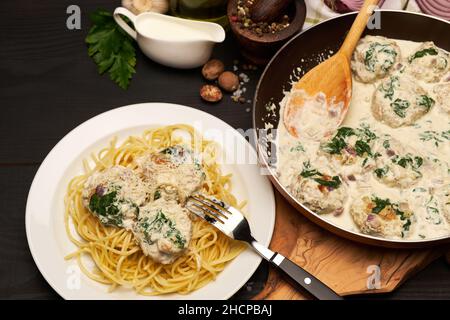 Portion leckere Fleischbällchen mit Spinat in einer cremigen Sauce Stockfoto