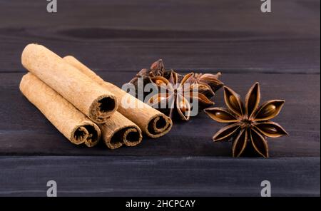 Würzige Zimtstangen und Anisnoten auf dunklem Holzhintergrund. Stockfoto