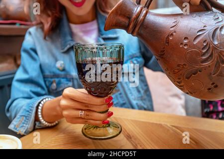 Eine Frau gießt georgischen Wein aus einem Tonkrug Stockfoto