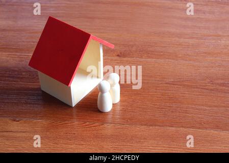 Familienplanung und Immobilienkonzept. Nahaufnahme des Holzspielzeughauses und der Puppen. Stockfoto