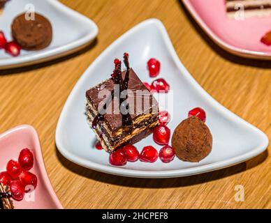Mehrere Gerichte mit geschichteten Donauwellendessert und Granatapfelsamen stehen eng beieinander auf einem Holztisch, fotografiert bei einer kulinarischen Veranstaltung in Grevenbroich, Deutschland. Stockfoto