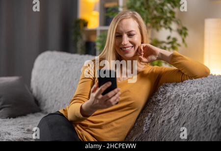 Frau mit Handy auf dem Sofa Stockfoto