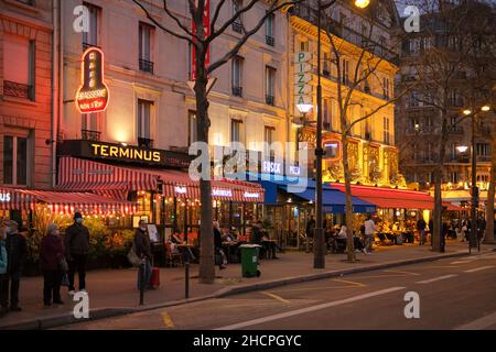 Paris, Frankreich - 30. Dezember 2021 : Blick auf eine typische geschäftige Pariser Straße mit Restaurants und Bars in der Nacht Stockfoto