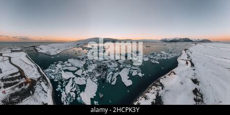 Luftdrohnenpanorama des berühmten Joekulsarlon-Sees und des Diamantenstrandes mit seinen Eisbergen und Eisschollen in Island während der Dämmerung bei Sonnenuntergang Stockfoto