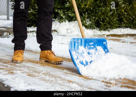 Entfernen von Schnee von der Auffahrt. Mann, der im Winter Schneeschaufel auf der Straße benutzt Stockfoto