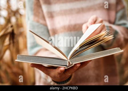 Buch in weiblicher Hand öffnen. Frau liest Buch im Freien Stockfoto