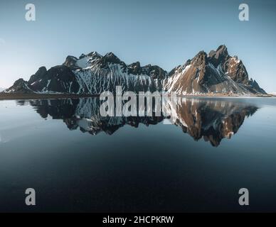 Luftdrohnenansicht eines herrlichen sonnigen Tages und einer wunderschönen Reflexion des Vestrahorn Bergs auf dem Stokksnes Kap in Island. Lage: Stokksnes Kap Stockfoto