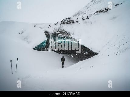 Blauer Kristall Eishöhle Eingang mit touristischen Kletterer und einem unterirdischen Fluss unter dem Gletscher in den Highlands in Island Stockfoto