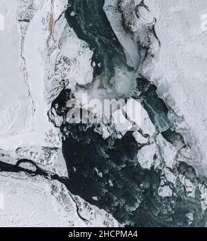 Drohnenaufnahme des Godafoss Wasserfalls, Island, aus einem hohen Winkel aufgenommen. Luftaufnahme der mächtigen Kaskade, des Flusses und der schneebedeckten Felsen. Spätherbst Stockfoto