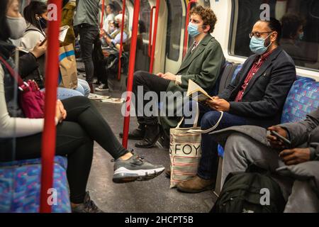 Menschen mit Gesichtsmasken während der Pandemie 19, Passagiere in einem U-Bahn-Wagen der Londoner U-Bahn, London, Großbritannien Stockfoto