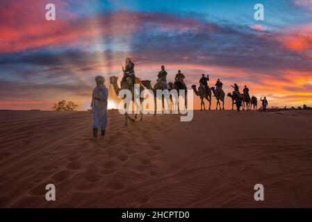 Beduinen führen Kamelkarawane mit Touristen durch den Sand in der Wüste Stockfoto