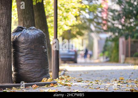 Stapel schwarzer Müllsäcke voller Müll, die auf der Straßenseite zur Abholung liegen. Abfallentsorgungskonzept. Stockfoto