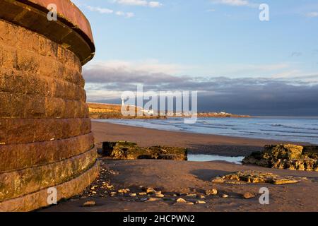 Am frühen Morgen fängt goldenes Licht die Meeresmauer am Roker Beach an, mit Blick nach Norden zum Weißen Leuchtturm in Sunderland, Tyne und Wear Stockfoto