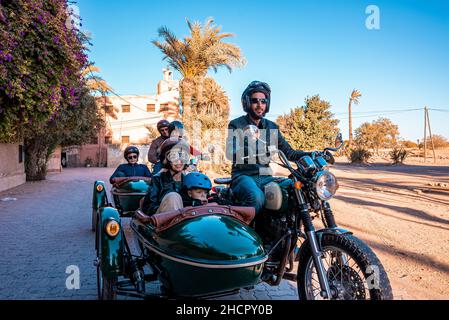 Gruppe von Leuten, die auf einem Oldtimer-Motorrad mit Seitenwagen unterwegs sind Stockfoto