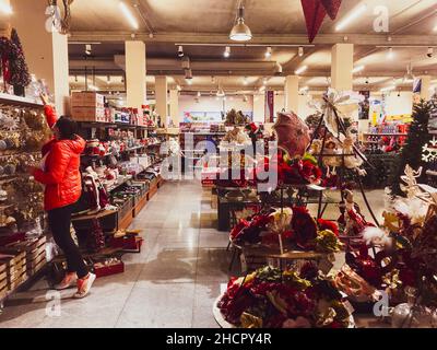 Tiflis, Georgien -10th november, 2021: Junge Frau Kunden nehmen von oben Regal Weihnachtsdekoration in spezialisierten Weihnachtsgeschäft Stockfoto