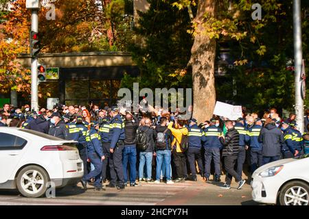 Tiflis, Georgien - 10th. november 2021: Polizeibeamte umgeben eine Menge aggressiver Demonstranten auf der Straße bei öffentlichen Anti-Regierung-Protesten Stockfoto