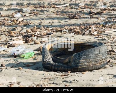 Reifen, Plastikflaschen und anderer Müll, der nach einem Sturm am Strand zurückgelassen wurde, ein Symbol für die schwere Verschmutzung der Meere und Ozeane Stockfoto