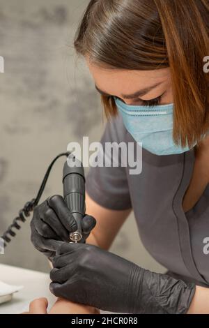 Manikurist entfernt Nagellack nutzt die elektrische Maschine der Nagelfeile während der Maniküre in einem Nagelstudio Stockfoto