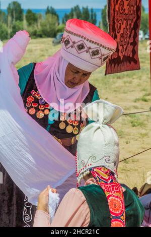 ISSYK KUL, KIRGISISTAN - 15. JULI 2018: Einheimische Frauen tragen traditionelle Kleidung beim Ethnofestival Teskey Jeek an der Küste des Issyk-Kul-Sees in Kirgisistan Stockfoto