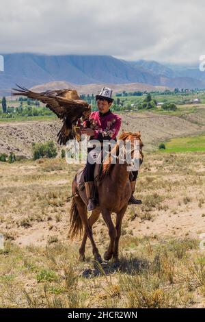 ISSYK KUL, KIRGISISTAN - 15. JULI 2018: Lokaler Jäger mit seinem Adler beim Ethnofestival Teskey Jeek an der Küste des Issyk Kul Sees in Kirgisistan Stockfoto