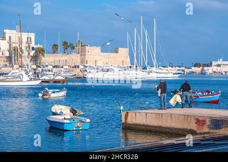 Blick auf Bari mit kleinem Hafen, alten Gebäuden und Palmen, bunten Holzbooten und Fischern im Hintergrund, Bari, Apulien, Italien Stockfoto