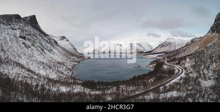 Blick vom touristischen Aussichtspunkt Bergsbotn auf die Halbinsel Senja im Norden Norwegens. Schneebedeckte Berggipfel umgeben ein Tal mit einer Bucht des No Stockfoto