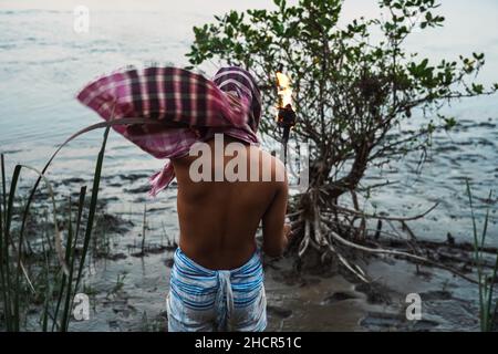 Ein Mann in Sundarban Flussseite mit einer Feuerfackel. Stockfoto