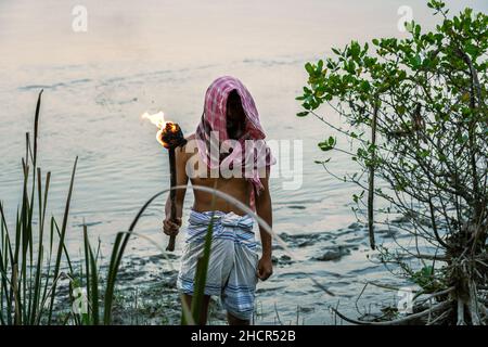 Ein Mann in Sundarban Flussseite mit einer Feuerfackel. Stockfoto