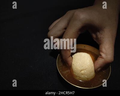 Hand Abholung nolen gur rosogolla oder rasgulla serviert auf dem Teller. Braun schwammig bengali indischen traditionellen süßen aus Quark und Jaggery. w Stockfoto