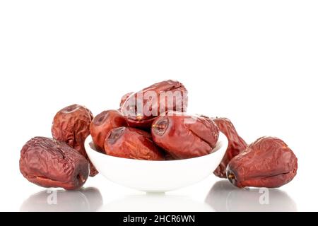 Mehrere süße getrocknete ziziphus-Beeren mit einer weißen Keramikuntertasse, Nahaufnahme, isoliert auf Weiß. Stockfoto