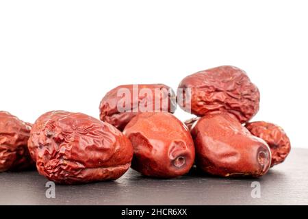 Mehrere süße getrocknete ziziphus-Beeren auf einem Schieferstein, aus der Nähe, isoliert auf weiß. Stockfoto