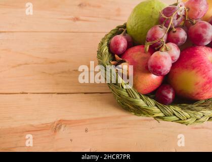 Verschiedene bunte Früchte in einem Korb gehalten. apfel, Granatapfel, Traube, Beere, Banane, Guava zusammen gehalten. Nahaufnahme. Copy Space Hintergrund. Stockfoto