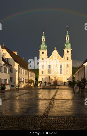 Arlesheimer Dom nach einem Gewitter. Der Himmel ist dunkel mit einem Regenbogen direkt über der Kuppel, die Abendsonne erleuchtet die Kathedrale. Arlesheim Stockfoto