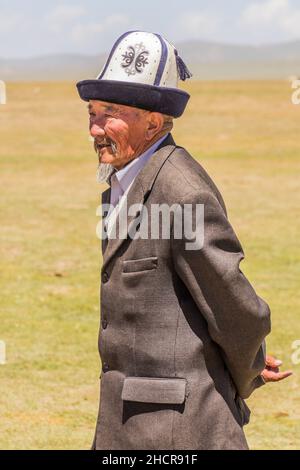 SONG KOL, KIRGISISTAN - 25. JULI 2018: Traditionelle Kleidung mit einem älteren Mann während des National Horse Games Festivals am Ufer des Son Kol Sees Stockfoto