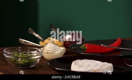 Nahaufnahme verschiedener Zutaten zum Kochen auf einem Holztisch auf grünem Wandhintergrund stehend. Chili, Cranberry, Mayonnaise und Senf-SA Stockfoto