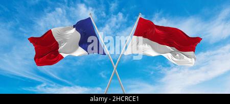 Gekreuzte Nationalflaggen von Frankreich und Monaco, die im Wind bei bewölktem Himmel winken. Symbolisiert Beziehung, Dialog, Reisen zwischen zwei Ländern. Stockfoto