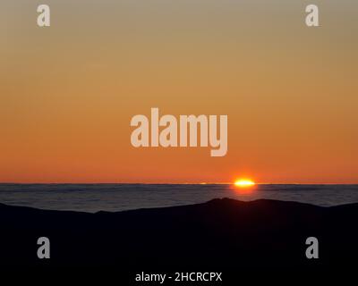 Der Blick auf den Sonnenuntergang über dem irischen Meer von den Coniston Fjälls mit Nebel von einer Temperaturinversion, Lake District, Großbritannien. Stockfoto