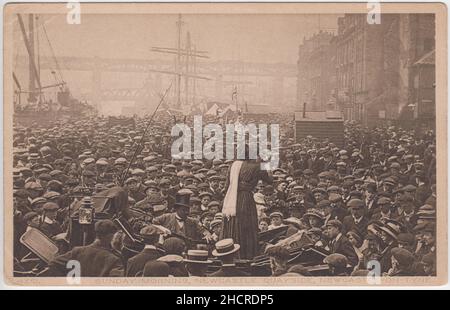 „Sonntagmorgen, Newcastle Quayside, Newcastle on Tyne“: Foto eines Massentreffens aus dem frühen 20th. Jahrhundert, das von einer in einem Wagen stehenden Frau, einem Mitarbeiter des Sprechers, einem gut gekleideten schwarzen Mann mit Zylinderhut, auf das Fahrzeug gelehnt wurde. Im Hintergrund sind Masten von Segelschiffen zu sehen. Das Thema des Treffens ist unklar, es gibt keine Banner mit Slogans und das Publikum ist größtenteils männlich (und trägt flache Kappen). Stockfoto