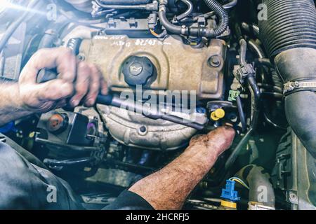 Auto-Mechaniker arbeiten an Motor in Mechaniker Garage. Reparaturservice. Authentische Nahaufnahme Stockfoto