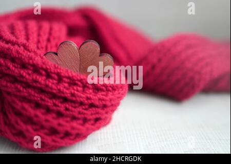 Valentinstagskonzept mit rotem Schal und Herzen auf grauem Hintergrund. Urlaubskonzept. Stockfoto