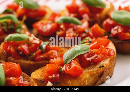 Leckere, herzhafte Tomaten, italienische Vorspeisen oder Bruschetta, auf Scheiben geröstetem Baguette, garniert mit Basilikum, aus nächster Nähe Stockfoto