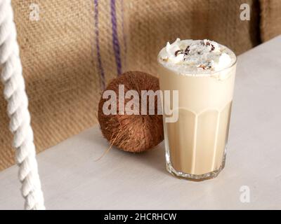 Coconut Latte in einem hohen Glas und Coconut auf einer Schaukel in einem Café. Nahaufnahme. Stockfoto