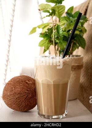 Coconut Latte in einem hohen Glas und Coconut auf einer Schaukel in einem Café. Nahaufnahme. Stockfoto